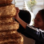 Apposer une feuille d'or sur la statue de Bouddha, en guise d'offrande: un geste habituel pour les bouddhistes en Thaïlande.